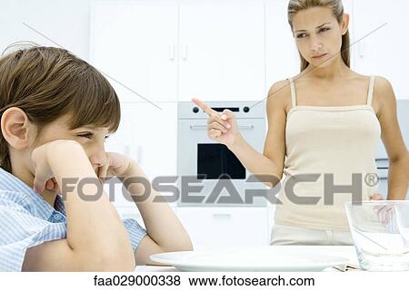 Boy pouting at kitchen table, mother shaking her finger View Large Photo Image Stock Photo - Boy pouting at kitchen table, mother shaking her finger. Fotosearch
