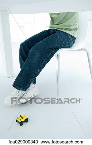 Boy sitting at table, toy car on the floor nearby, cropped view View Large Photo Image Stock Image - Boy sitting at table, toy car on the floor nearby, cropped view. Fotosearch