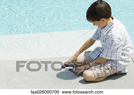 Boy sitting on ground, playing with toy cars, next to pool View Large Photo Image Stock Image - Boy sitting on ground, playing with toy cars, next to pool. Fotosearch