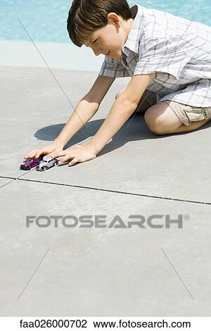 Boy sitting on ground, playing with toy cars, next to pool View Large Photo Image Stock Image - Boy sitting on ground, playing with toy cars, next to pool. Fotosearch