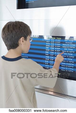 Boy standing looking at arrival board, pointing to line on screen View Large Photo Image Stock Image - Boy standing looking at arrival board, pointing to line on screen. Fotosearch
