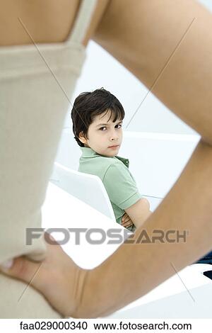 Boy sulking, looking over shoulder at mother in foreground with hand on hip View Large Photo Image Stock Image - Boy sulking, looking over shoulder at mother in foreground with hand on hip. Fotosearch