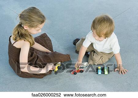 Brother and sister sitting on the ground, playing with toy cars, high angle view View Large Photo Image Stock Image - Brother and sister sitting on the ground, playing with toy cars, high angle view. Fotosearch