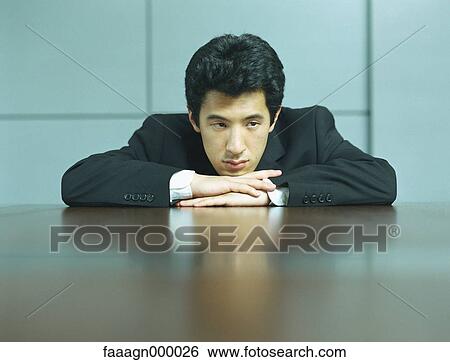 Stock Photograph - Businessman resting head on hands, portrait. Fotosearch