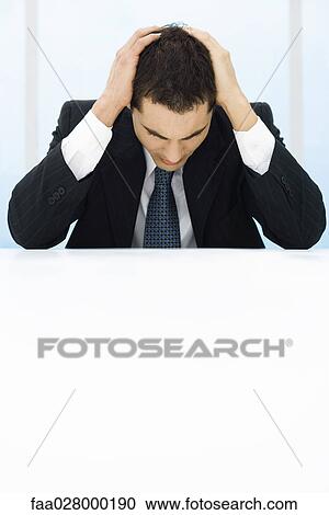 Businessman sitting, holding head, looking down View Large Photo Image Stock Image - Businessman sitting, holding head, looking down. Fotosearch