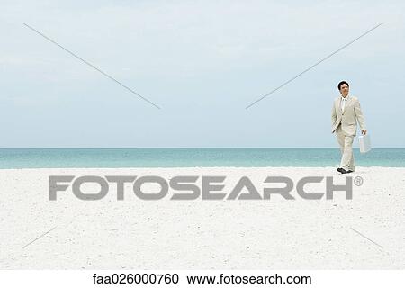 Businessman walking across beach, carrying briefcase View Large Photo Image Stock Image - Businessman walking across beach, carrying briefcase. Fotosearch