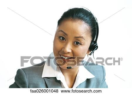 Stock Photo - Businesswoman wearing headset, smiling at camera, close-up. Fotosearch