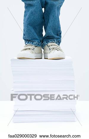 Child standing on tall stack of papers, low angle view, cropped View Large Photo Image Stock Photo - Child standing on tall stack of papers, low angle view, cropped. Fotosearch