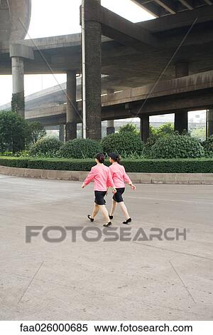 China, Guangzhou, two woman wearing matching uniforms walking under bridge, rear view View Large Photo Image Stock Photography - China, Guangzhou, two woman wearing matching uniforms walking under bridge, rear view. Fotosearch