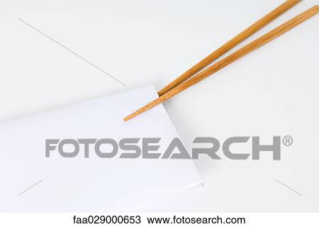 Stock Image - Chopsticks holding folded napkin, close-up. Fotosearch