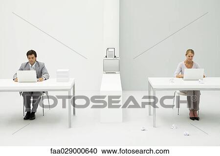 Colleagues in office using laptop computers, printer between them with graphic of document, paper balls scattered on the floor View Large Photo Image Stock Image - Colleagues in office using laptop computers, printer between them with graphic of document, paper balls scattered on the floor. Fotosearch