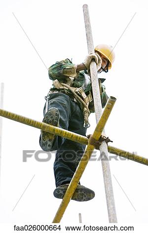 Picture - Construction worker standing on scaffolding, low angle view. Fotosearch