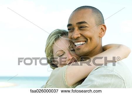 Couple embracing and smiling outdoors, woman's eyes closed View Large Photo Image Stock Photo - Couple embracing and smiling outdoors, woman's eyes closed. Fotosearch