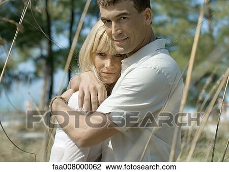 Stock Image - Couple embracing in coastal setting. Fotosearch
