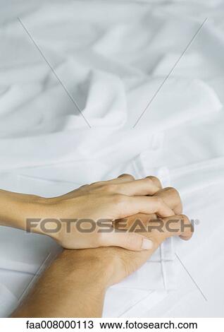 Couple holding hands on sheets, close-up View Large Photo Image Stock Image - Couple holding hands on sheets, close-up. Fotosearch