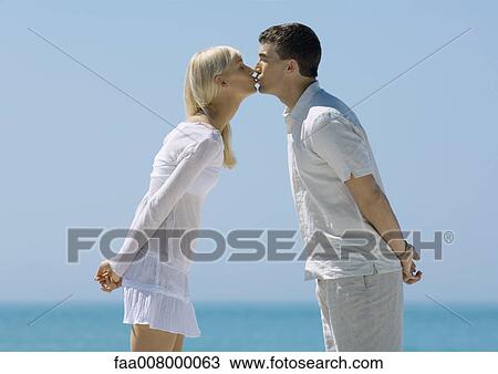 Couple leaning forward, kissing, sea in background View Large Photo Image Stock Image - Couple leaning forward, kissing, sea in background. Fotosearch