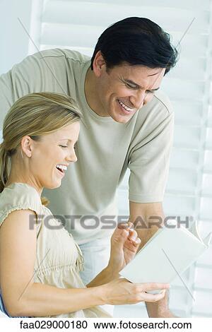 Couple reading book together, man looking over woman's shoulder, both smiling View Large Photo Image Stock Image - Couple reading book together, man looking over woman's shoulder, both smiling. Fotosearch