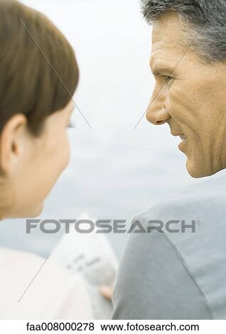 Couple reading newspaper together, water in background View Large Photo Image Stock Photo - Couple reading newspaper together, water in background. Fotosearch