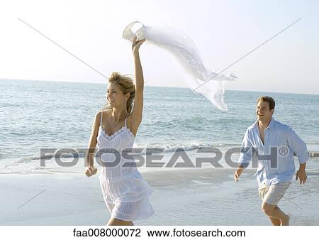 Stock Image - Couple running on beach. Fotosearch