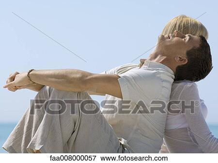 Couple sitting near sea, man resting head on woman's shoulder View Large Photo Image Stock Photo - Couple sitting near sea, man resting head on woman's shoulder. Fotosearch
