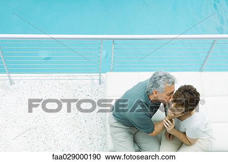 Couple sitting on balcony, man kissing woman's cheek, high angle view View Large Photo Image Stock Image - Couple sitting on balcony, man kissing woman's cheek, high angle view. Fotosearch