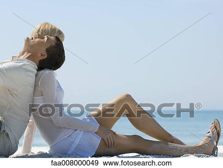 Couple sitting on beach, back to back View Large Photo Image Stock Photo - Couple sitting on beach, back to back. Fotosearch