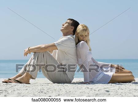 Couple sitting on beach, back to back View Large Photo Image Stock Photography - Couple sitting on beach, back to back. Fotosearch