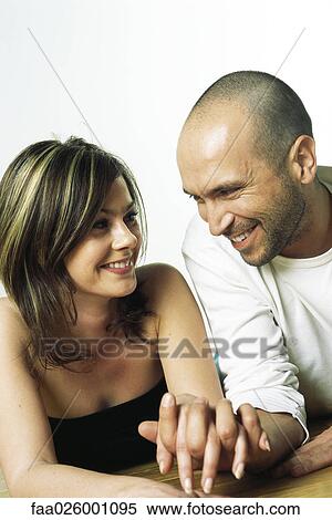 Couple sitting side by side, holding hands, smiling at each other View Large Photo Image Stock Photography - Couple sitting side by side, holding hands, smiling at each other. Fotosearch