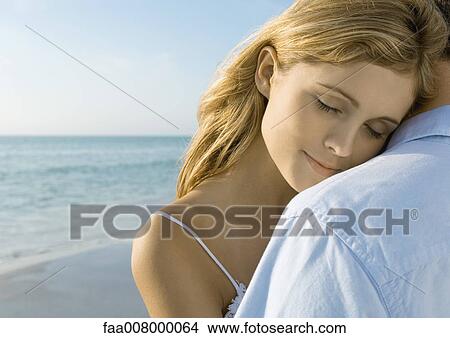 Couple standing on beach, woman resting head on man's shoulder View Large Photo Image Picture - Couple standing on beach, woman resting head on man's shoulder. Fotosearch