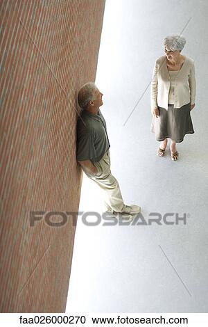 Couple talking together, man leaning against wall with hands in pockets, high angle view View Large Photo Image Stock Image - Couple talking together, man leaning against wall with hands in pockets, high angle view. Fotosearch