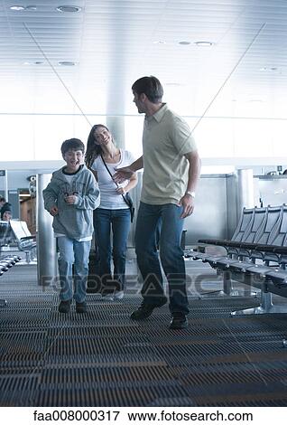 Family hurrying through airport, man reaching back to wife View Large Photo Image Stock Photo - Family hurrying through airport, man reaching back to wife. Fotosearch