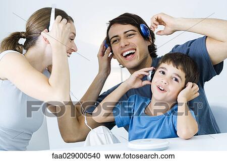 Stock Image - Family listening to CD player together, father and son using wireless headphones. Fotosearch