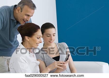 Family looking at cell phone together, smiling View Large Photo Image Stock Photo - Family looking at cell phone together, smiling. Fotosearch