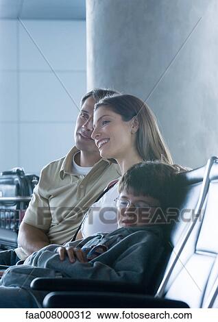 Stock Image - Family sitting in airport lounge, boy sleeping. Fotosearch