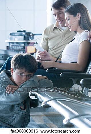 Family sitting in airport lounge, boy on floor, leaning on seat View Large Photo Image Stock Photograph - Family sitting in airport lounge, boy on floor, leaning on seat. Fotosearch
