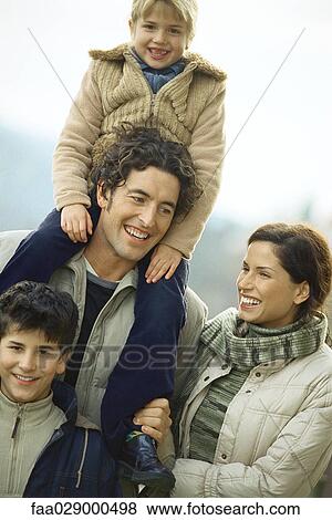 Stock Photo - Family wearing winter clothes outdoors, smiling, portrait. Fotosearch