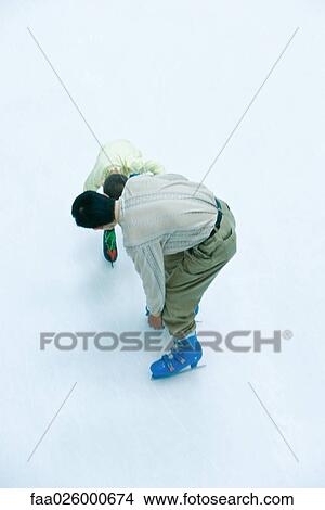 Father and son ice skating together, both bending over, high angle view View Large Photo Image Picture - Father and son ice skating together, both bending over, high angle view. Fotosearch