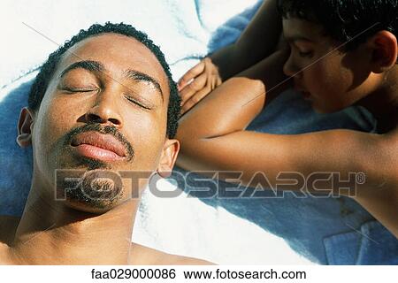 Father and son lying on the ground, eyes closed, close-up View Large Photo Image Stock Photograph - Father and son lying on the ground, eyes closed, close-up. Fotosearch