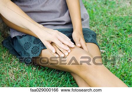 Stock Photograph - Female sitting on the ground, holding woman's hand, cropped view. Fotosearch