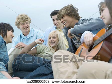 Friends hanging out together, one playing guitar View Large Photo Image Stock Image - Friends hanging out together, one playing guitar. Fotosearch