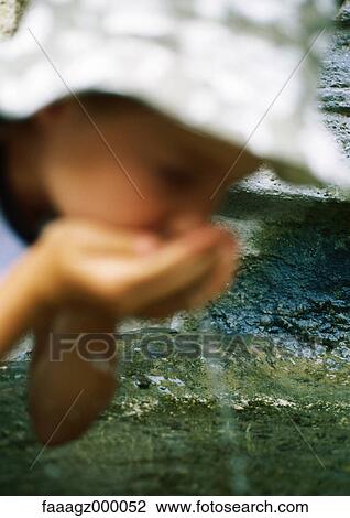 Stock Image - Girl drinking water from cupped hands. Fotosearch