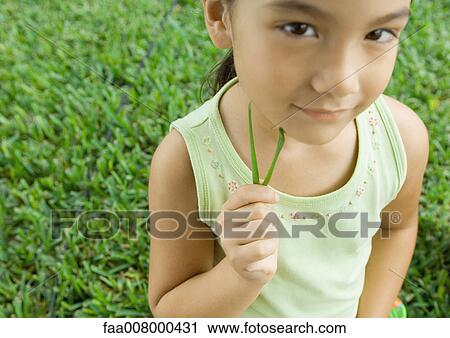Girl holding blades of grass to cheek View Large Photo Image Stock Image - Girl holding blades of grass to cheek. Fotosearch