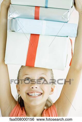 Girl holding stack of presents on head View Large Photo Image Stock Photograph - Girl holding stack of presents on head. Fotosearch