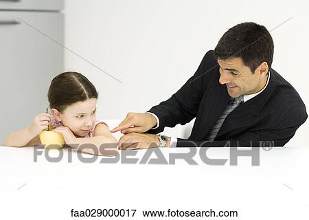 Stock Photo - Girl protecting bowl of cereal while father teases her. Fotosearch