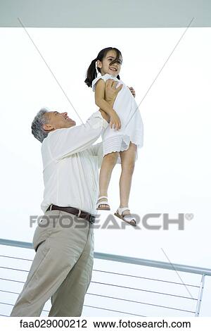 Grandfather holding granddaughter up in the air, both smiling, low angle view View Large Photo Image Stock Image - Grandfather holding granddaughter up in the air, both smiling, low angle view. Fotosearch