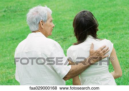 Grandfather with hand on teen granddaughter's shoulder outdoors, rear view View Large Photo Image Stock Photo - Grandfather with hand on teen granddaughter's shoulder outdoors, rear view. Fotosearch