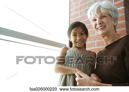 Grandmother and granddaughter holding hands, both smiling, low angle view View Large Photo Image Stock Image - Grandmother and granddaughter holding hands, both smiling, low angle view. Fotosearch
