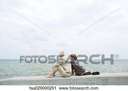 Grandmother and grandson sitting together by the sea, looking at view, rear view View Large Photo Image Stock Image - Grandmother and grandson sitting together by the sea, looking at view, rear view. Fotosearch