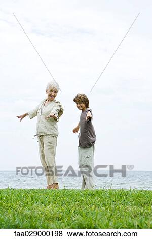 Grandmother and grandson standing outdoors with arms out, both smiling at camera, ocean in background View Large Photo Image Stock Photo - Grandmother and grandson standing outdoors with arms out, both smiling at camera, ocean in background. Fotosearch