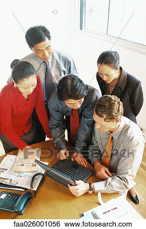 Group of professionals looking down at laptop computer together, high angle view View Large Photo Image Stock Photograph - Group of professionals looking down at laptop computer together, high angle view. Fotosearch